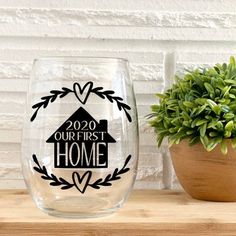 a wine glass sitting on top of a wooden table next to a potted plant