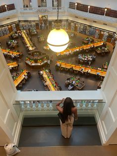 a woman looking down at a library filled with lots of book shelves and bookshelves