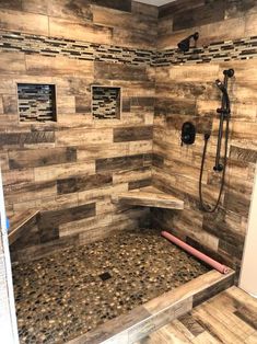 a walk in shower sitting next to a tiled wall and wooden tile flooring on the walls