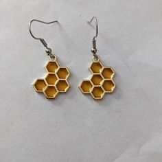 the earrings are made out of metal and have honeycombs hanging from each ear