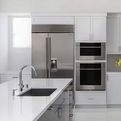 a modern kitchen with stainless steel appliances and white countertops