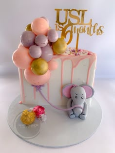 a birthday cake with balloons and an elephant figurine