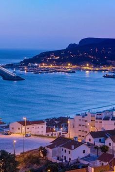 an aerial view of a city by the ocean at night with boats in the water