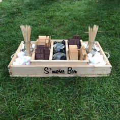 a wooden box filled with candles and marshmallows on top of green grass