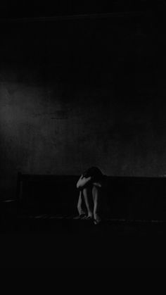 a person sitting on a bench in the dark