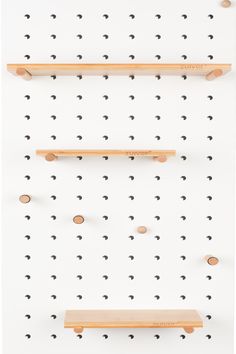 three wooden shelves mounted to the wall with pegs on them and one shelf holding several different types of items