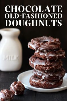 chocolate old - fashioned doughnuts are stacked on a plate with white frosting