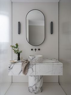 a bathroom with marble counter top and round mirror