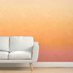 a white couch sitting in front of a wall with an orange and pink painted background