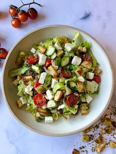 a white bowl filled with salad next to cherry tomatoes