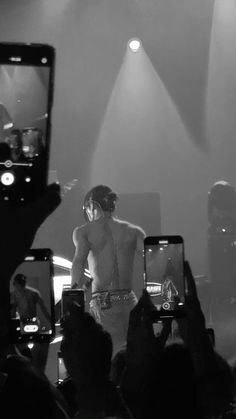 a man standing on top of a stage holding two cell phones in front of him