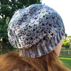 a woman with red hair wearing a crocheted hat on her head in the park