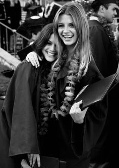 two women in graduation gowns hugging each other