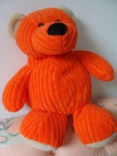 an orange teddy bear sitting on top of a bed