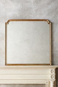 a white fireplace mantel with a mirror above it