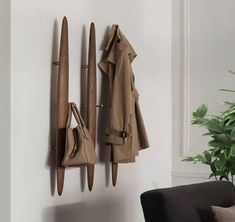 a coat rack with two coats hanging from it's sides next to a couch