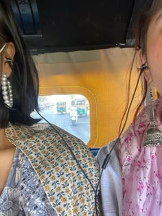 two young women sitting in the back of a car with ear rings on their ears