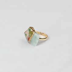 a gold ring with a green stone in the middle on a white tablecloth background