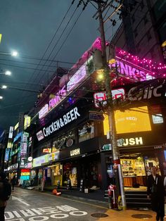 a city street filled with lots of neon signs and people walking on the side walk