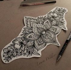 a piece of paper with flowers and leaves on it next to a pen, scissors and ink