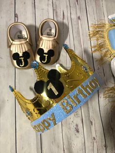 two baby shoes and a gold crown on a wooden floor