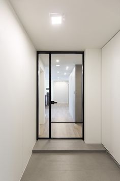 an empty white room with glass doors leading to another room and a door in the middle