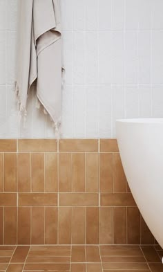 a white bath tub sitting next to a tiled wall