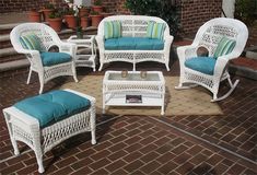 white wicker patio furniture set with blue cushions on brick flooring and potted plants