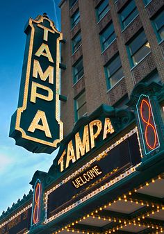 the tampa amp sign is lit up at night in front of a tall building with lights on it