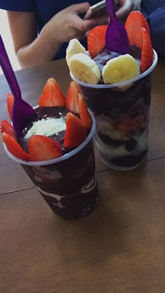 two cups filled with ice cream and strawberries on top of a table next to each other