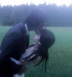 a man and woman kissing in the middle of a field