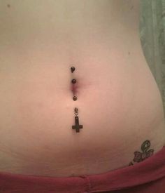 a woman's stomach with a cross tattoo on the side and beads attached to it