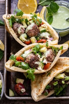 three pita breads filled with meatballs and veggies on a tray