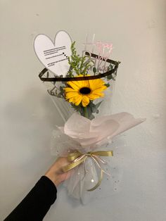 a person holding a bouquet of flowers in front of a white wall with happy birthday written on it