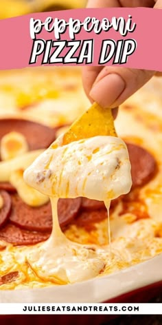 a person dipping cheese on top of a pizza with pepperoni and other toppings