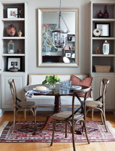 a dining room table with chairs and a couch in front of a bookcase filled with books