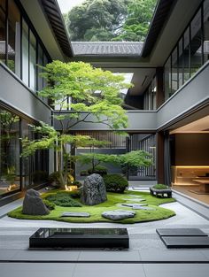 an indoor courtyard with green grass and rocks in the center, surrounded by tall trees