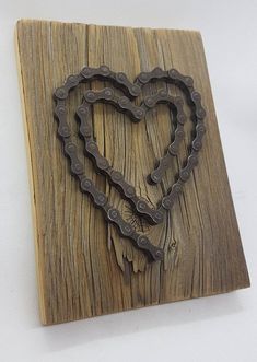 a heart made out of bike chains on a wooden plaque with white background and clippings