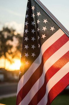 an american flag with the sun setting behind it