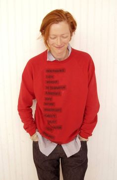 a woman wearing a red sweater with words on the front and back of her shirt