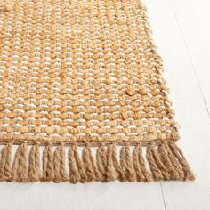 an area rug with fringes on top of white wood flooring in a room