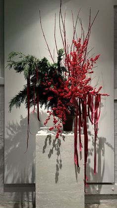 a vase filled with red flowers sitting on top of a white table next to a wall