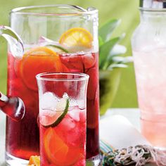 two pitchers filled with different types of drinks on top of a table next to each other