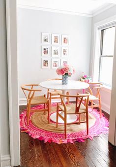 a white table and chairs in a small room with pink rugs on the floor