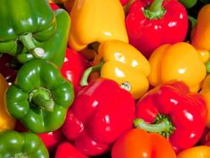 many different colored peppers are stacked up in the same pile and one is yellow, green, red, orange