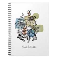 a spiral notebook with an illustration of flowers and leaves on the cover, says keep smiling