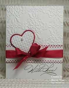 a white card with red ribbon and a heart on it