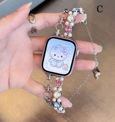 a person holding an apple watch with charms on it's wrist and bracelets around their wrists