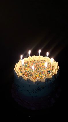 a birthday cake with lit candles and sprinkles