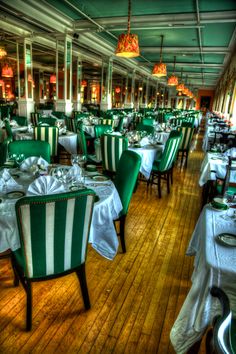 a restaurant with green and white striped chairs, tablecloths and plates on the tables